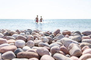 Två personer badar i havet vid en vacker stenstrand på Gotska Sandön
