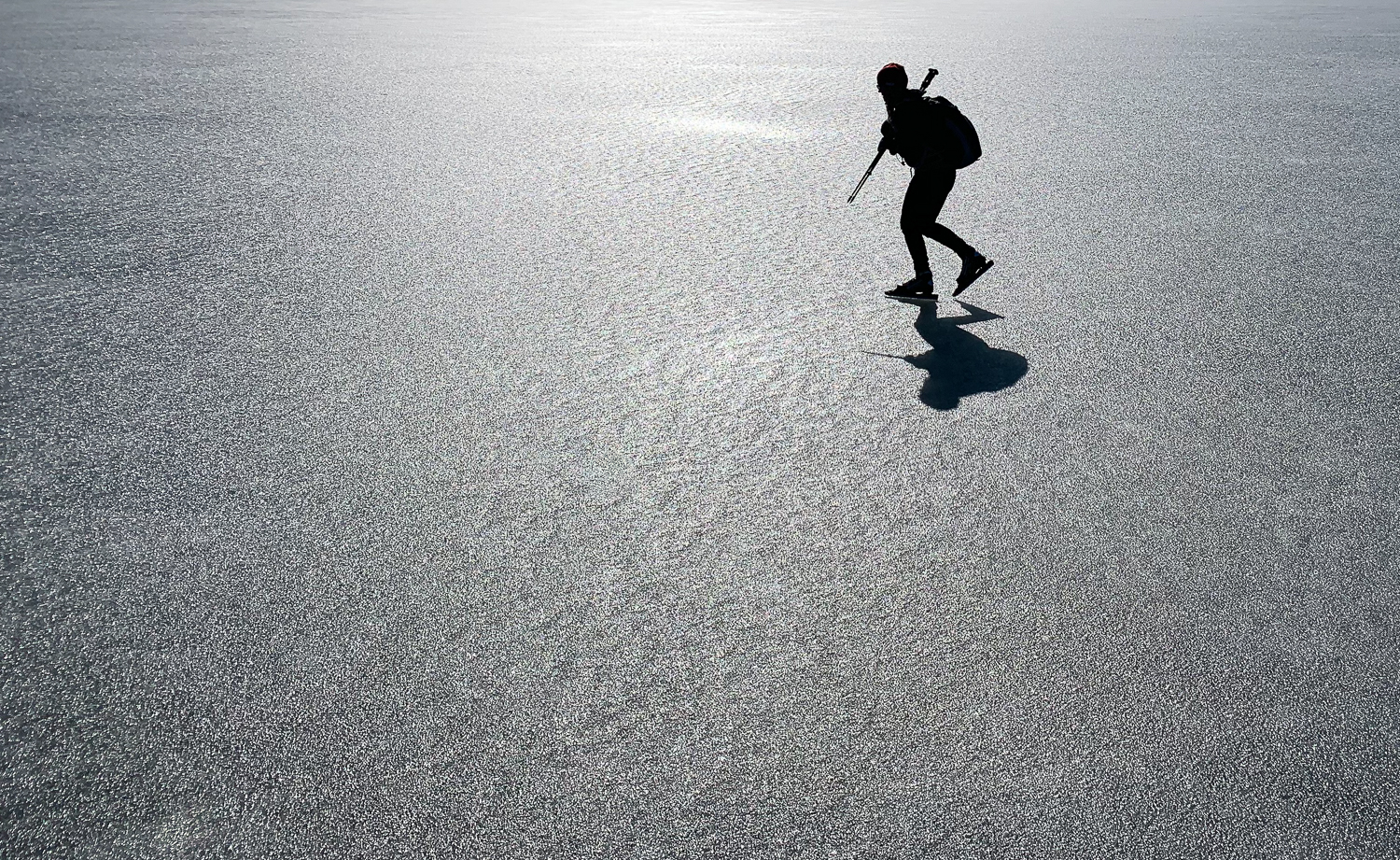 Långfärdskridskoåkare i motljus på sjön Båven, Sörmland